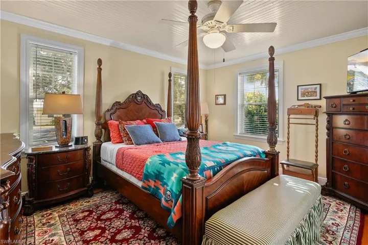 Owners suite featuring ceiling fan on wood plank ceiling with crown molding, and hand scraped hard wood floors. Great natural lighting with multiple windows and french doors to the screened porch.