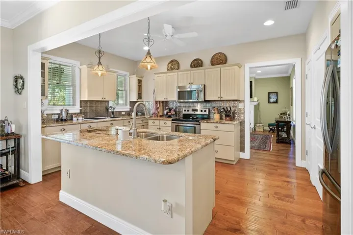 Wonderful kitchen for entertaining! Kitchen featuring a kitchen island with sink and dishwasher, appliances with stainless steel finishes, light stone countertops, pendant lighting and built-in grill/griddle.
