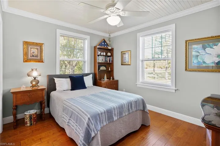 Guest bedroom with ceiling fan, ornamental molding, and hand scrapped hardwood floor.