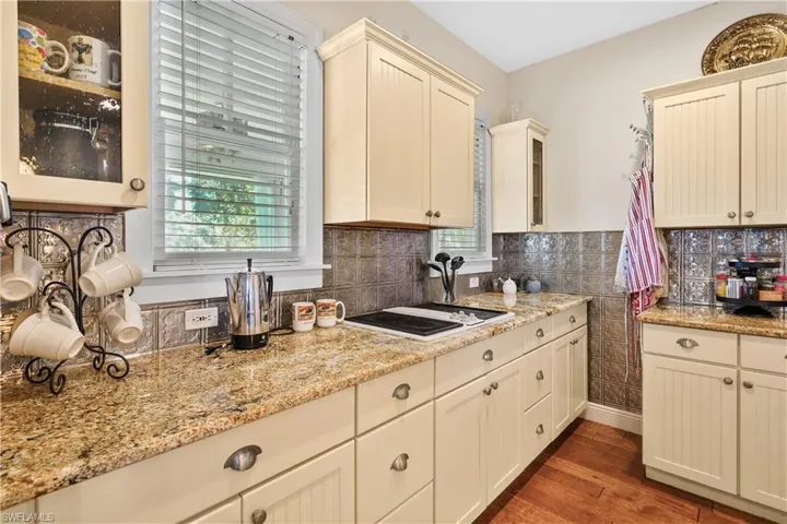 Kitchen with light stone counters, tasteful backsplash, cream cabinetry, and beautiful hand scraped hardwood floors. You'll enjoy the built in grill/ griddle.
