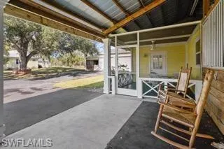 Back barn has a lot of covered area outside the stalls. View of apartment screen porch overlooking large oak tree with circle bench in the center of the circle drive way.