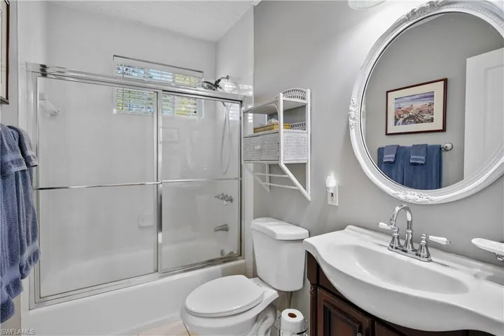 Full guest bathroom with shower / bath combination with glass door, vanity, and toilet