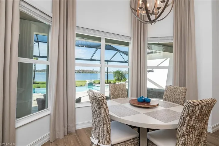 Dining room featuring a water view, wood finished floors, a chandelier, a sunroom, and plenty of natural light