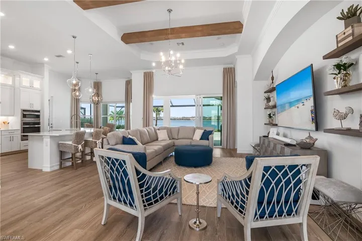 Living room featuring a chandelier, crown molding, light wood-style flooring, and beamed ceiling