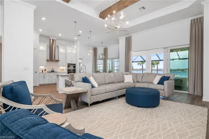 Living area with crown molding, a water view, recessed lighting, a chandelier, and light wood finished floors