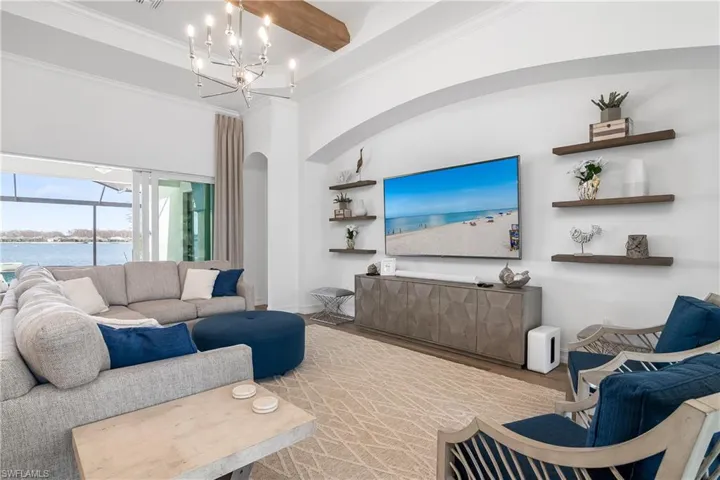 Living room with a water view, wood finished floors, ornamental molding, and a high ceiling