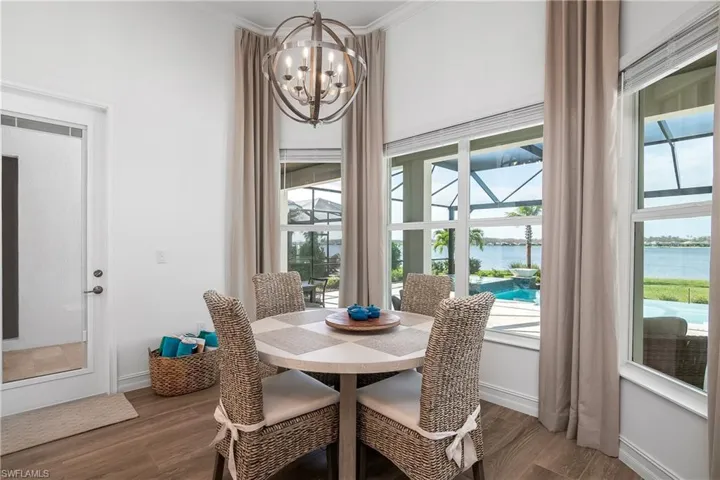 Dining room with a water view, a chandelier, dark wood-style floors, and crown molding