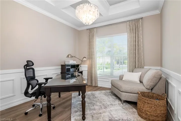 Home office with a wainscoted wall, a decorative wall, a chandelier, coffered ceiling, and wood finished floors
