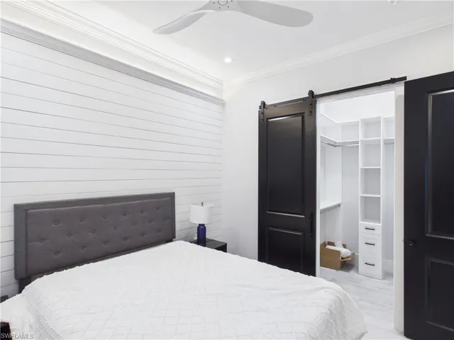 Bedroom featuring a shiplap accent wall, crown molding, and a ceiling fan