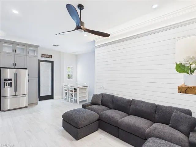 Open-concept living area with shiplap accent wall, light wood-finish flooring, recessed lighting, and a modern ceiling fan