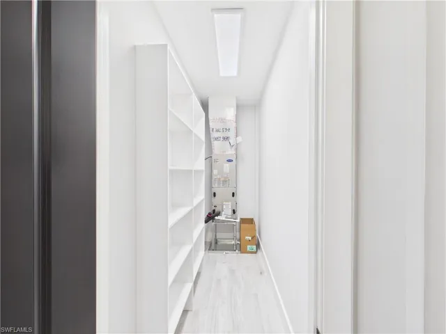Utility closet with extensive built-in shelving, wood-finish flooring, and a flush-mount ceiling light