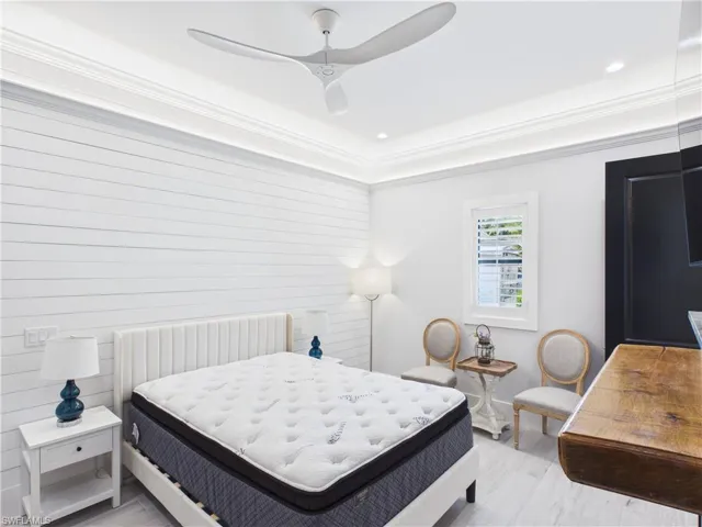 Bedroom featuring shiplap accent wall, crown molding, tray ceiling with recessed lighting, and a ceiling fan
