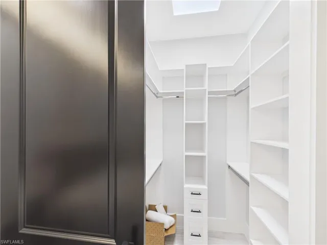 Walk-in closet featuring built-in shelving, hanging rods, an integrated drawer unit, and a skylight