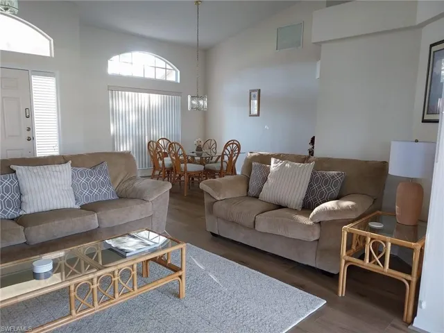 Living room with high vaulted ceiling, wood finished floors, and a chandelier