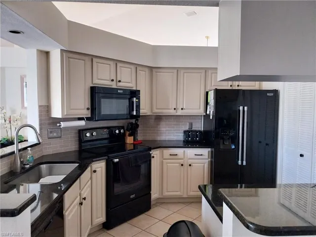 Kitchen featuring black appliances, tasteful backsplash, and light tile patterned flooring