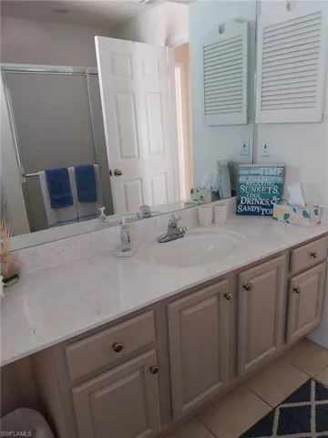 Full bathroom with light tile patterned floors, vanity, and a shower stall