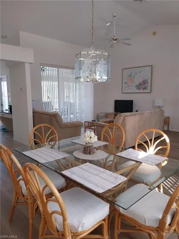 Dining space featuring wood finished floors, vaulted ceiling, and a ceiling fan