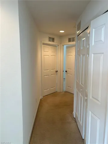 Hallway with light colored carpet and baseboards