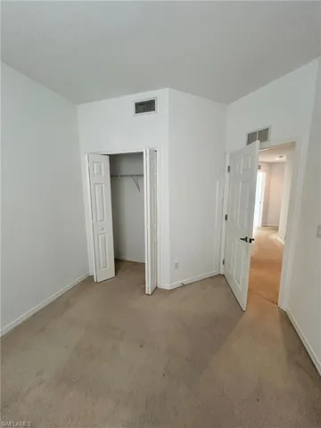 Unfurnished bedroom featuring light carpet and a closet
