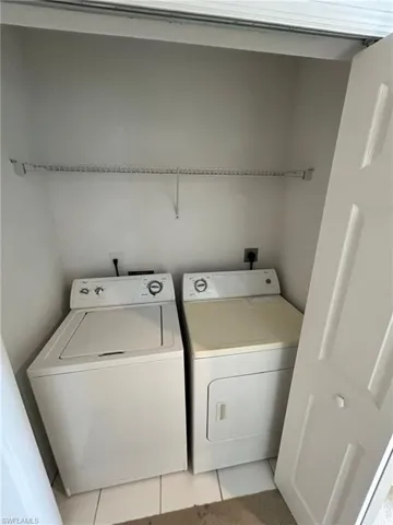 Laundry area with light tile patterned floors and separate washer and dryer
