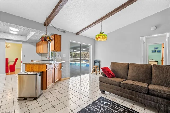 Living area featuring a textured ceiling, beam ceiling, and light tile patterned floors