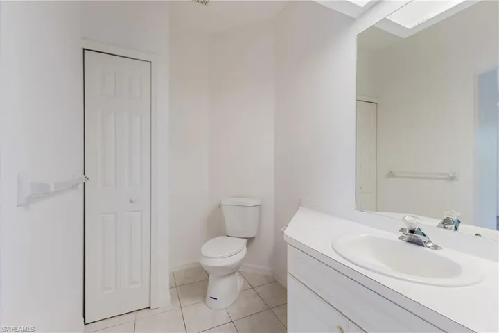 Bathroom featuring a closet, light tile patterned flooring, vanity, and a skylight