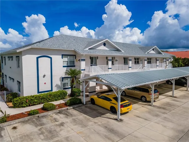 View of building exterior with covered parking and stairs