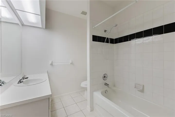 Full bath with washtub / shower combination, vanity, and light tile patterned flooring