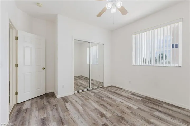 Unfurnished bedroom with multiple windows, light wood-style floors, a ceiling fan, and a closet