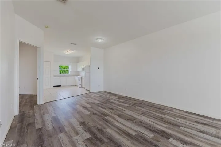 Unfurnished living room featuring light wood-style floors and baseboards