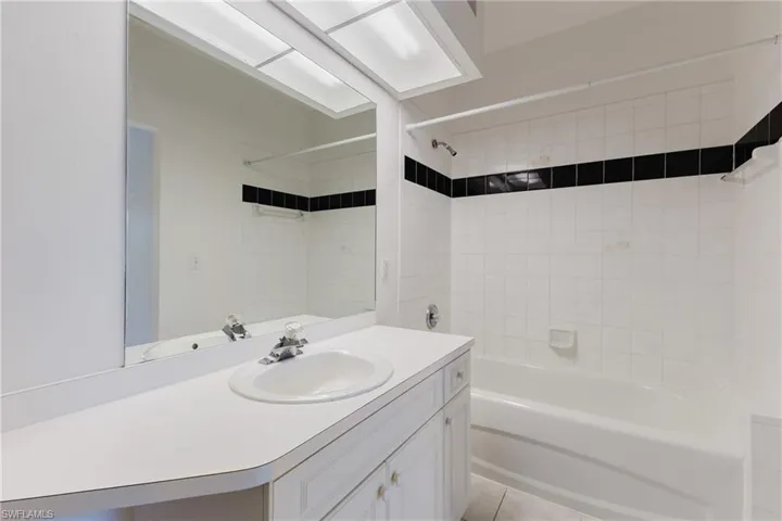 Bathroom featuring shower / bathtub combination, vanity, and light tile patterned flooring
