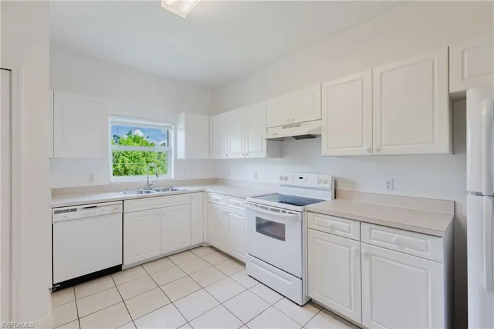 Kitchen featuring white appliances, light countertops, white cabinetry, and light tile patterned floors