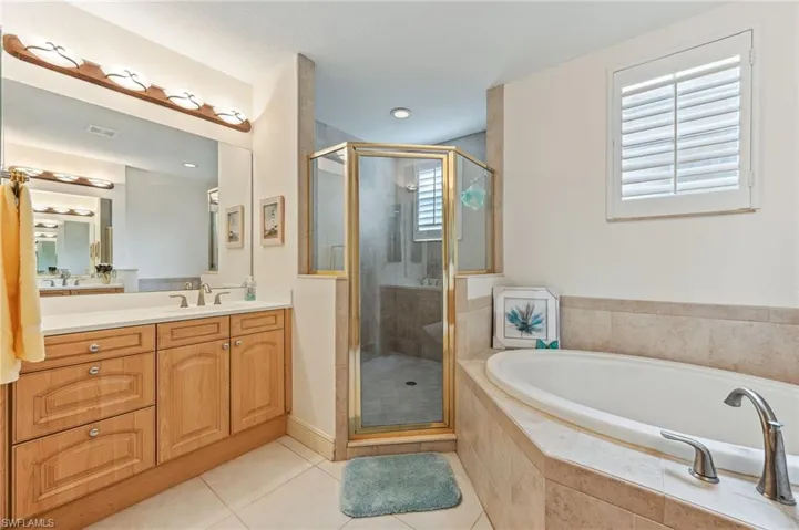Primary bathroom featuring independent shower and bath, vanity, and tile patterned flooring