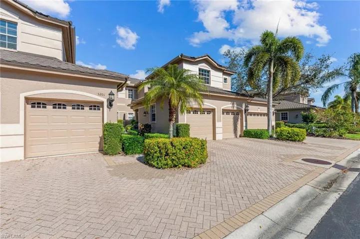 Front exterior view of coach home featuring attached 2-car garage and brick pavers