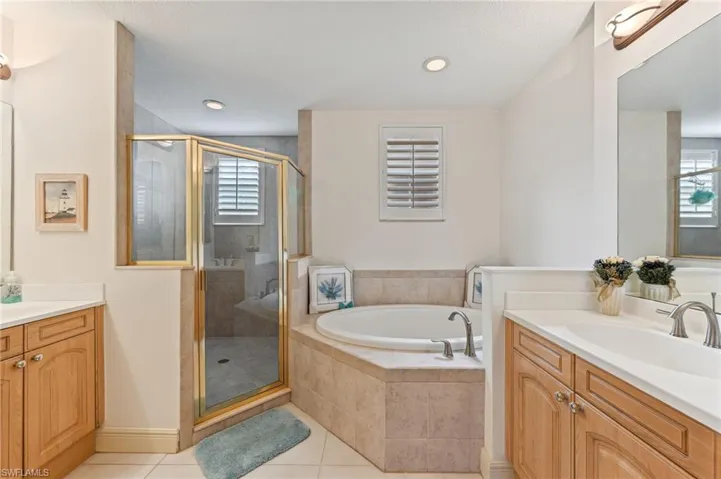 Primary bathroom featuring tile patterned flooring, plus walk in shower, a wealth of natural light, and vanity