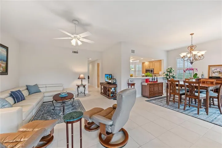 Living room with light tile patterned floors and ceiling fan with notable chandelier
