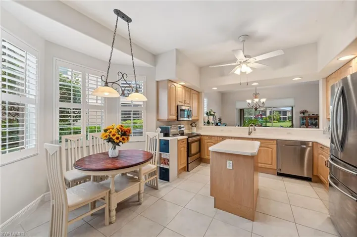 Kitchen with sink, light tile patterned floors, appliances with stainless steel finishes, and center island