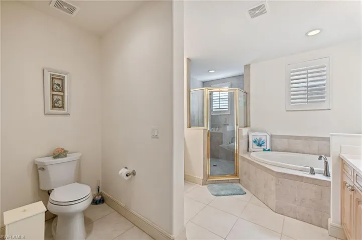 Primary bathroom with tile patterned flooring, vanity, independent shower and bath, and toilet