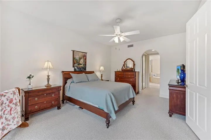 Guest bedroom featuring ceiling fan, light colored carpet, and connected bathroom