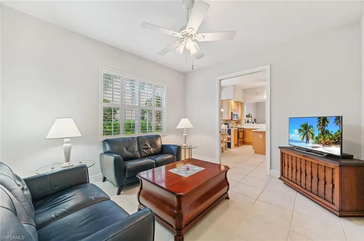 Den/office with light tile patterned floors and ceiling fan