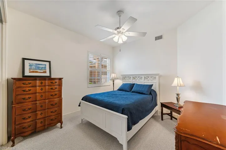 Guest bedroom featuring light carpet, lofted ceiling, and ceiling fan
