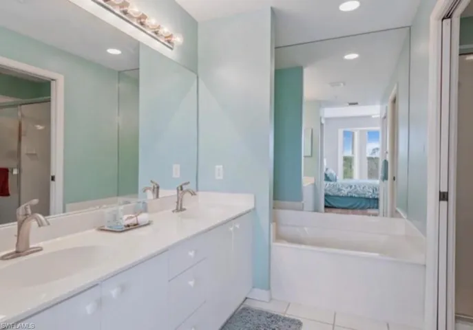 Primary Full bath featuring tile patterned floors, a shower stall, double vanity, a bath, and connected bathroom