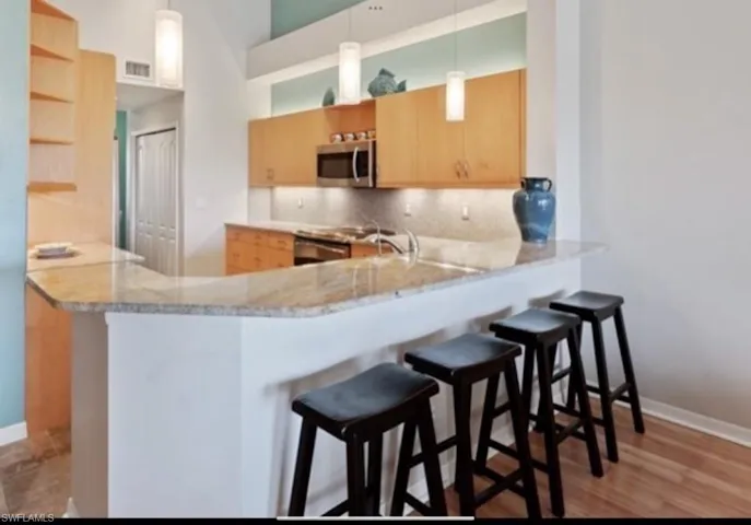 Kitchen featuring stainless steel microwave, open shelves, a peninsula, tasteful backsplash, and stove