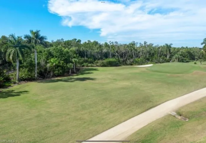 View of community with a putting area, view of golf course, and a lawn