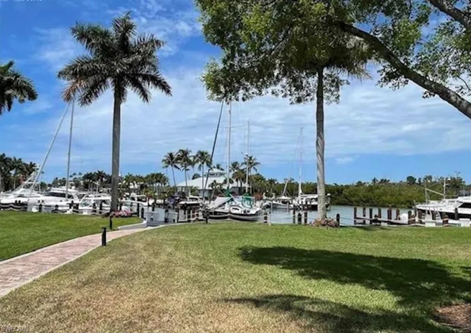 Surrounding community featuring a boat dock, a yard, and a water view