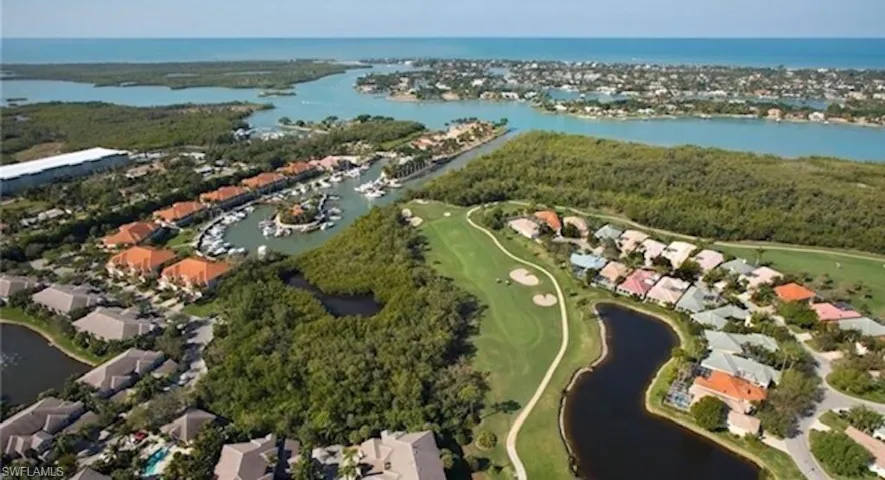 Aerial view of property and surrounding area featuring nearby suburban area, a large body of water, and a golf club