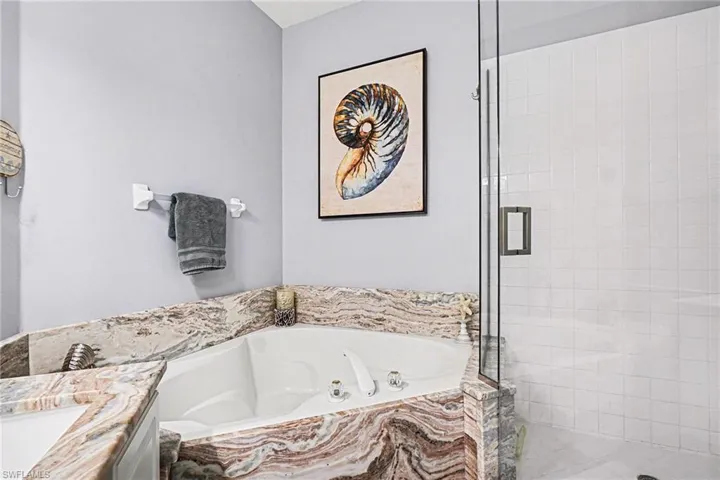 Full bath featuring vanity, a shower stall, and a garden tub