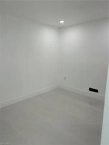 White-painted room featuring large format floor tiling, recessed ceiling lighting, and crisp baseboard trim
