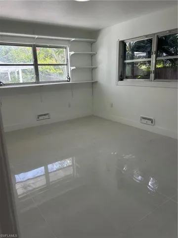 Room featuring a white color palette, glossy tile flooring, dual windows, and built-in shelving