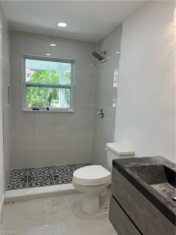 Modern bathroom featuring a walk-in shower with patterned floor tile, light-toned wall tiling, and a rainfall showerhead
